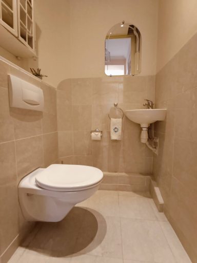 Toilettes modernes avec carrelage clair, lavabo et miroir sur le mur.