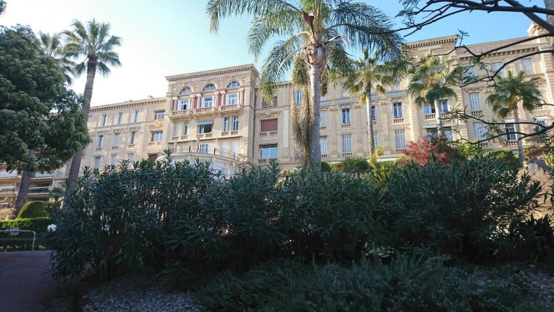 Bâtiment historique avec palmiers et jardin verdoyant devant lui.